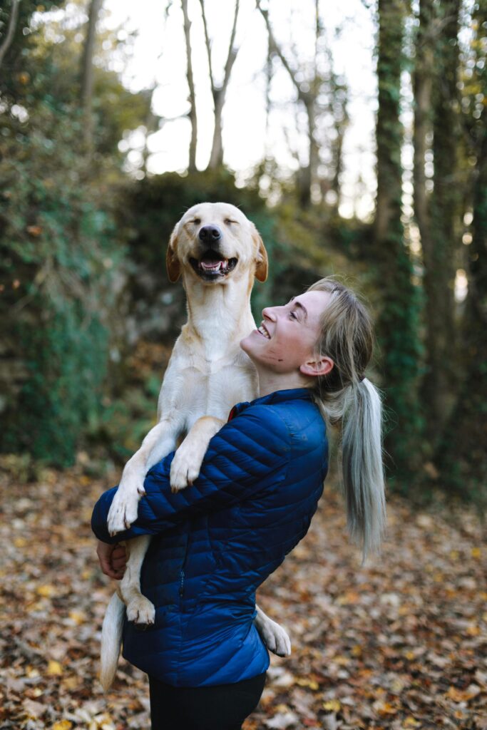 Lady holding large beige dog while hiking